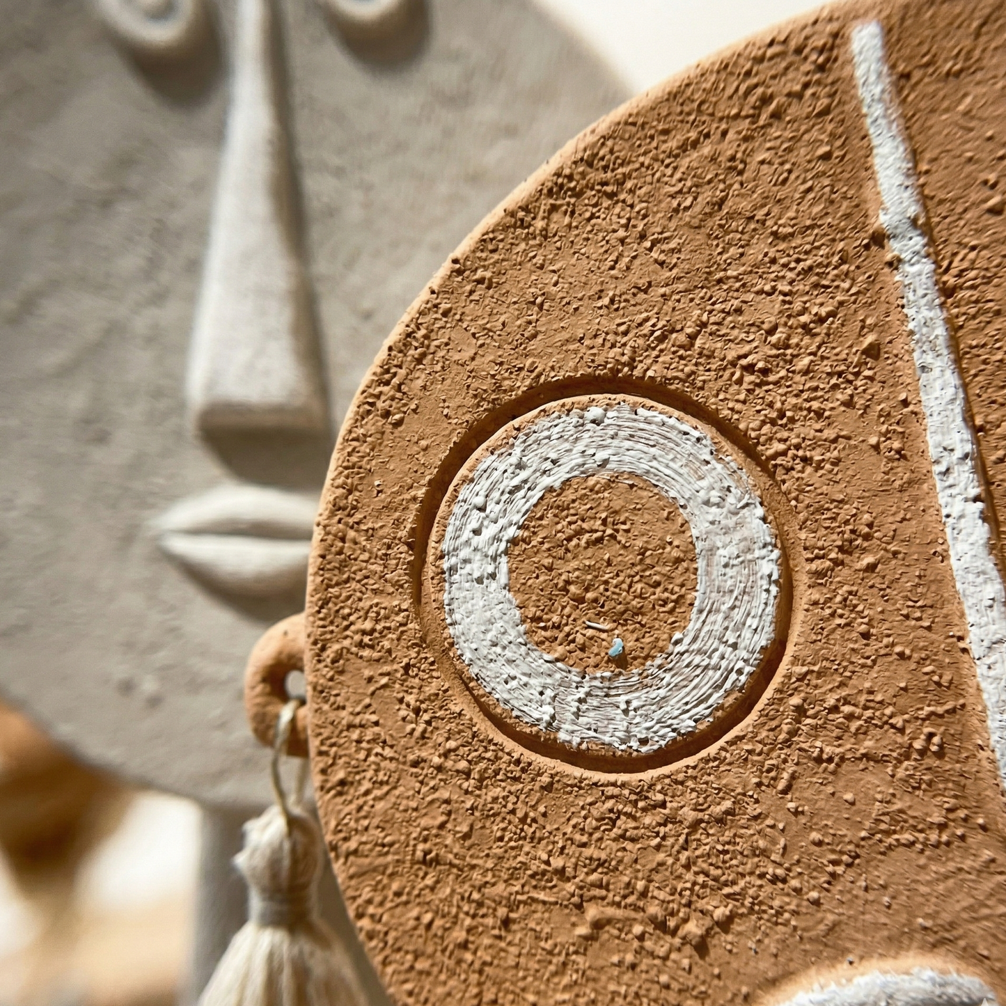 Close-up of a textured ceramic mask with circular design