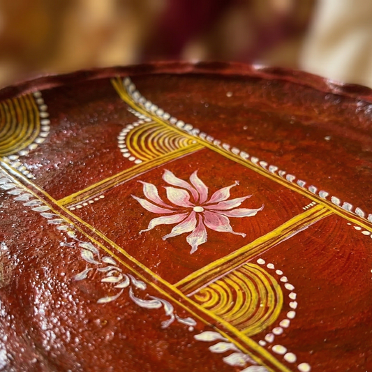 Decorative red plate with floral design on a blurred background