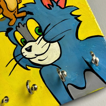 Close-up of hand painted texture  on wooden wall hanging featuring tom and jerry